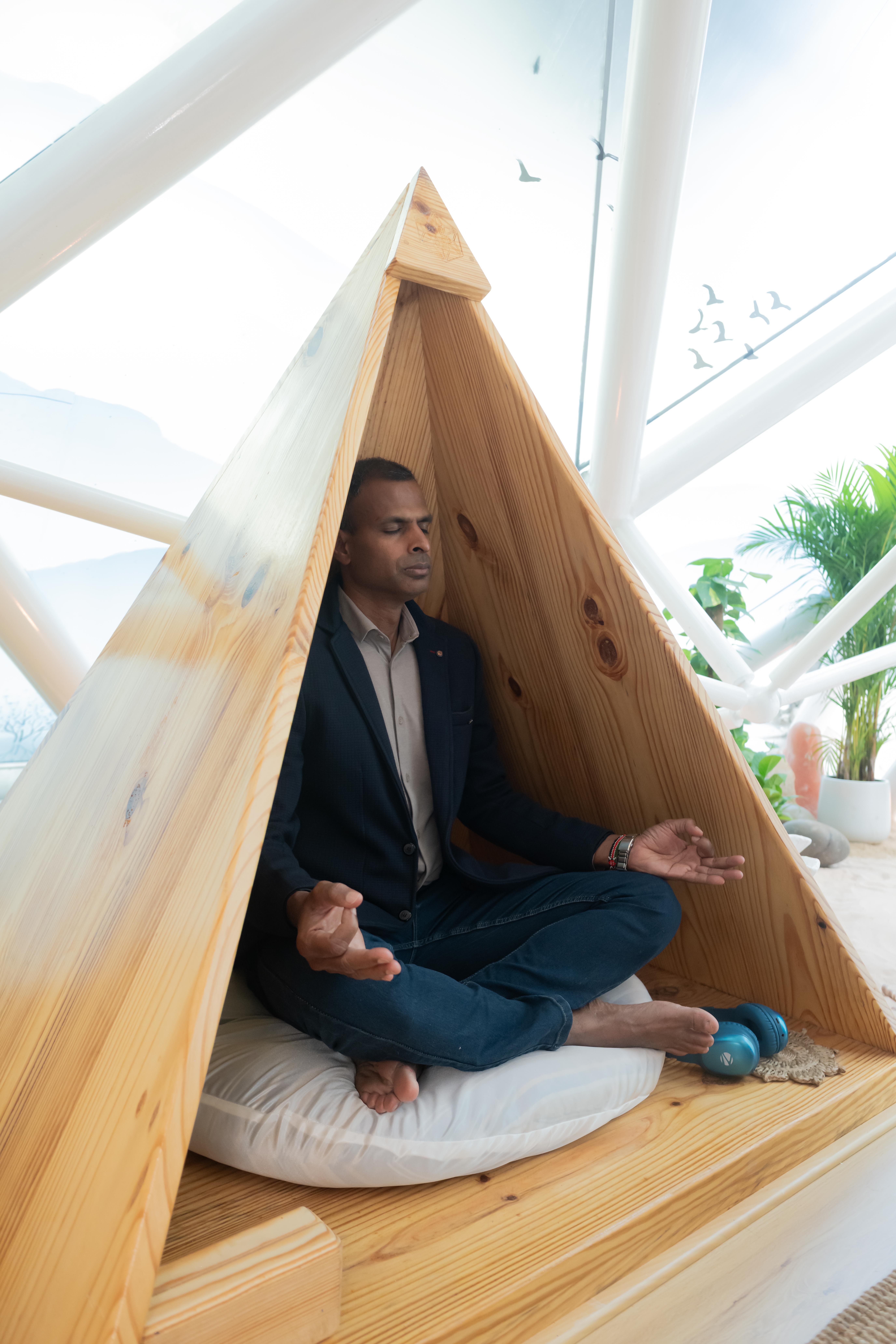 A founder seated in meditation inside the Bliss Zone pyramid nook