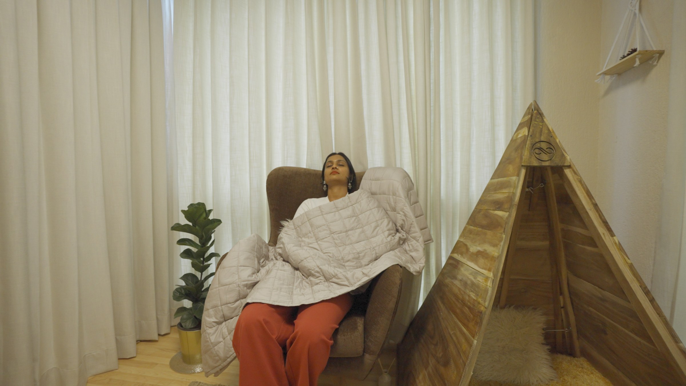 Employee resting under a weighted blanket in the Bliss Zone tent